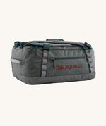 Patagonia black hole 40l duffel bag in noble grey available at Babipur. A dark grey bag with green trim and brown branding on the side. Features shoulders straps and a handle on the top for easy carrying.