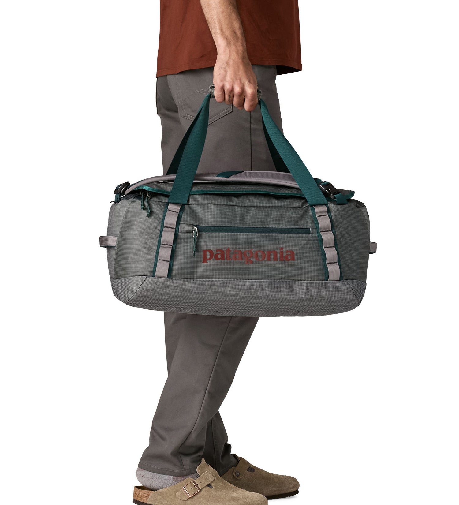 A man carrying the Patagonia black hole 40l duffel bag in noble grey available at Babipur. 
