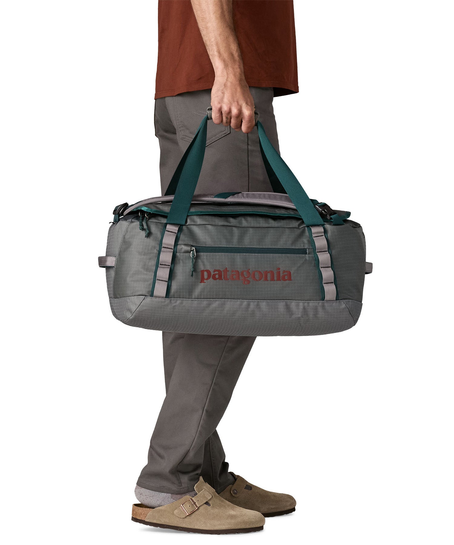 A man carrying the Patagonia black hole 40l duffel bag in noble grey available at Babipur. 