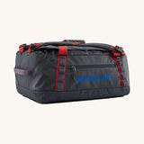Patagonia black hole 40l duffel bag in smolder blue / amanita red available at Babipur. A dark blue bag with red trim and blue branding on the side. Features shoulders straps and a handle on the top for easy carrying.
