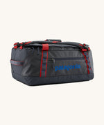 Patagonia black hole 40l duffel bag in smolder blue / amanita red available at Babipur. A dark blue bag with red trim and blue branding on the side. Features shoulders straps and a handle on the top for easy carrying.