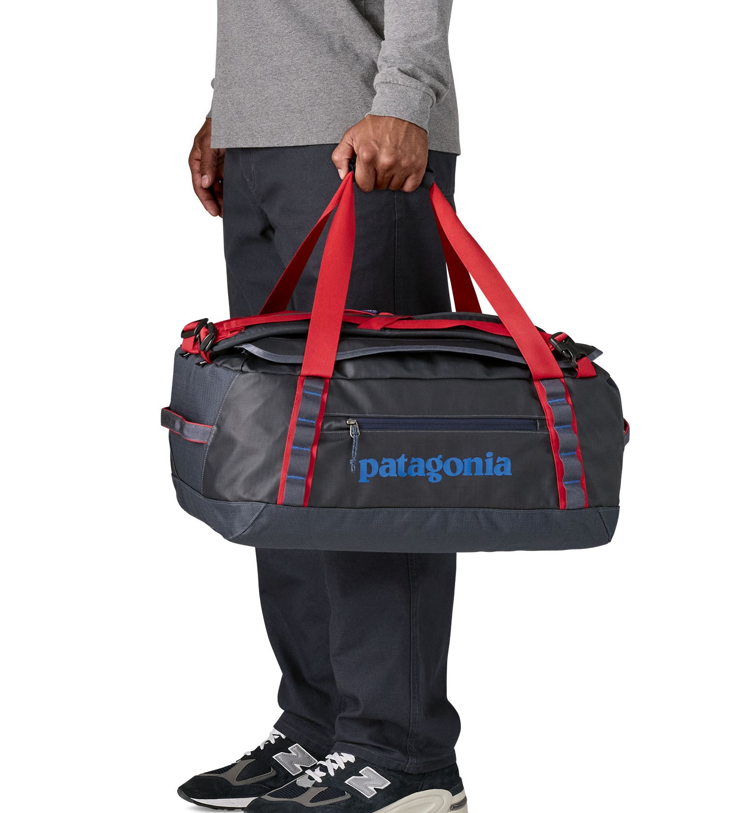 A man carrying the Patagonia black hole 40l duffel bag in smolder blue / amanita red available at Babipur. 
