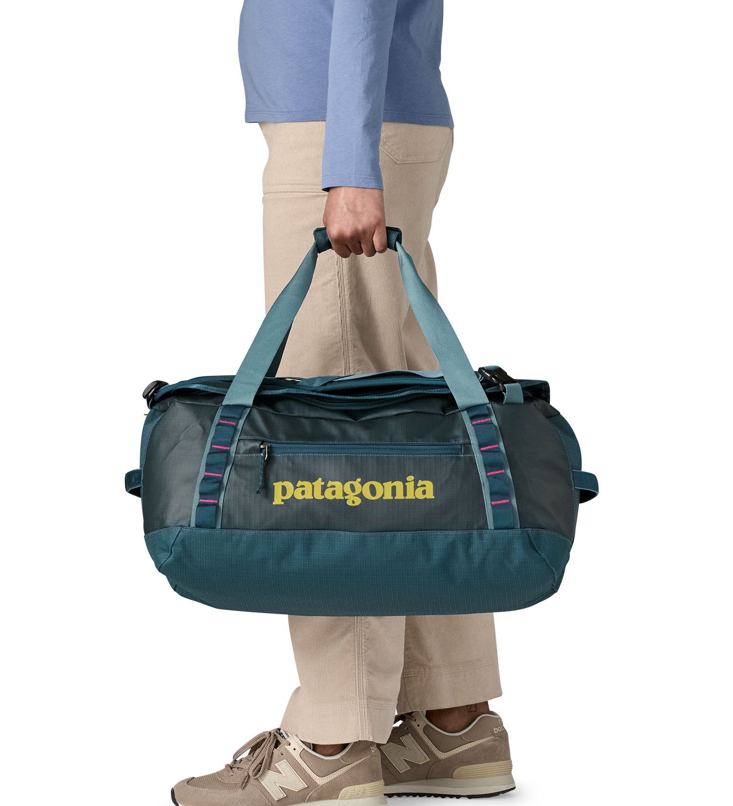A woman carrying the Patagonia black hole 40l duffel bag in tidal teal / luminous pink available at Babipur. 