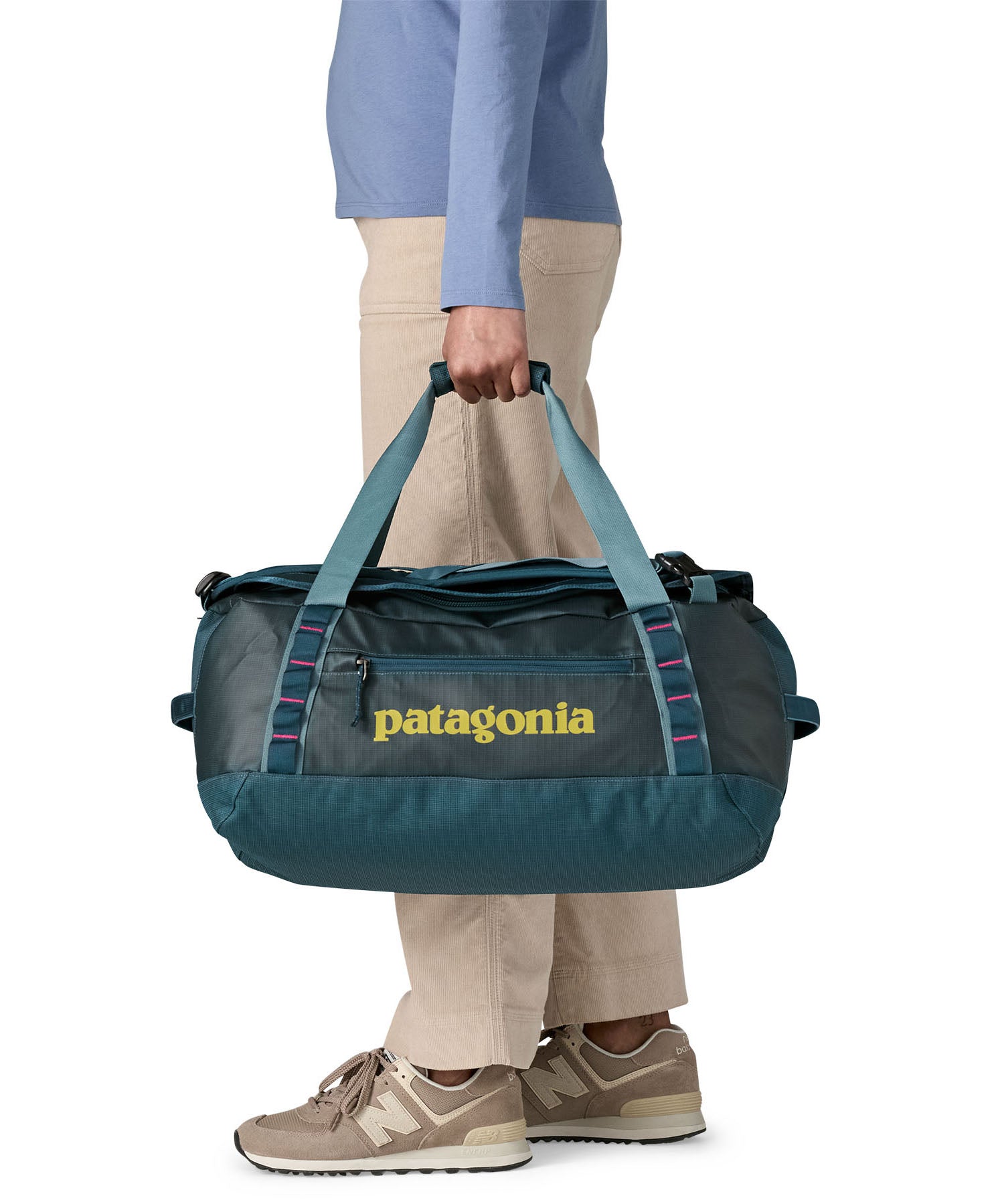 A woman carrying the Patagonia black hole 40l duffel bag in tidal teal / luminous pink available at Babipur. 