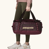 Patagonia Black Hole Duffel 40L in Berry Fig. Bag being held by handle straps. 