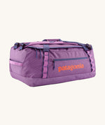 Patagonia black hole 55L duffel bag in brisk purple available at Babipur. A bright purple bag with orange branding on the side. Features shoulders straps and a handle on the top for easy carrying.