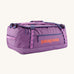 Patagonia black hole 55L duffel bag in brisk purple available at Babipur. A bright purple bag with orange branding on the side. Features shoulders straps and a handle on the top for easy carrying.