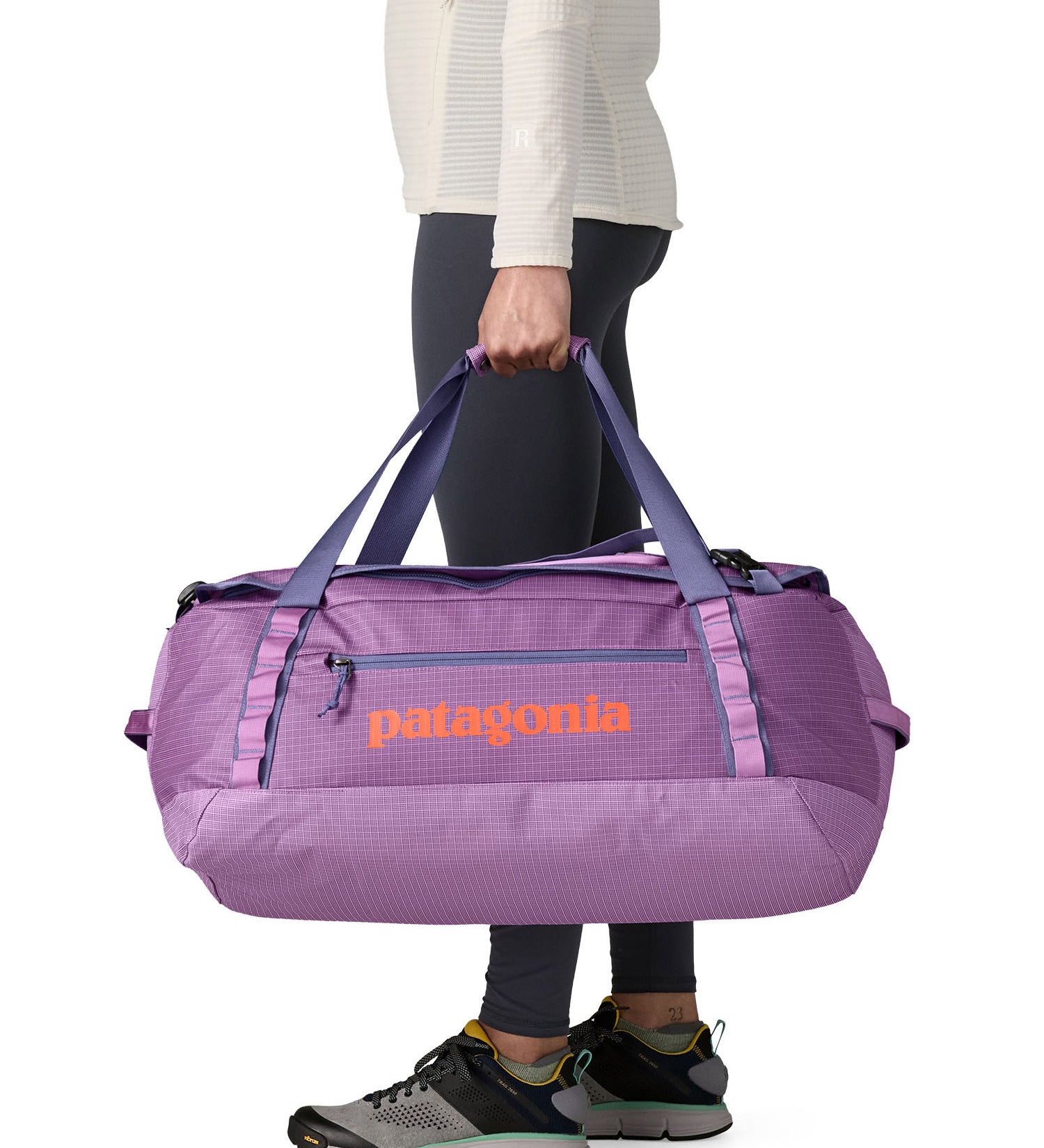 A woman carrying the Patagonia black hole 55L duffel bag in brisk purple available at Babipur. 