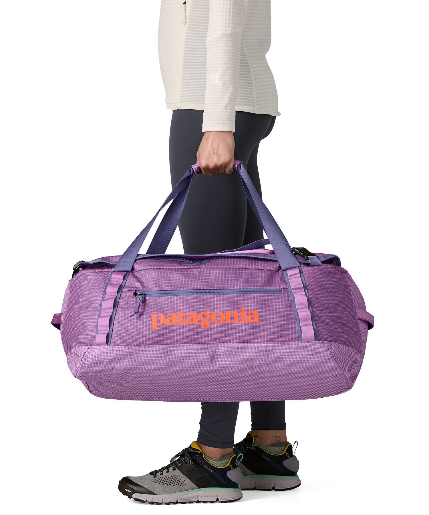 A woman carrying the Patagonia black hole 55L duffel bag in brisk purple available at Babipur. 
