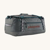 Patagonia black hole 55L duffel bag in noble grey available at Babipur. A dark grey bag with green trim and brown branding on the side. Features shoulders straps and a handle on the top for easy carrying.