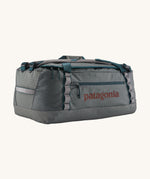 Patagonia black hole 55L duffel bag in noble grey available at Babipur. A dark grey bag with green trim and brown branding on the side. Features shoulders straps and a handle on the top for easy carrying.