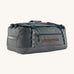 Patagonia black hole 55L duffel bag in noble grey available at Babipur. A dark grey bag with green trim and brown branding on the side. Features shoulders straps and a handle on the top for easy carrying.