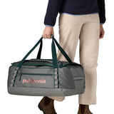 A woman carrying the Patagonia black hole 55L duffel bag in noble grey available at Babipur. 