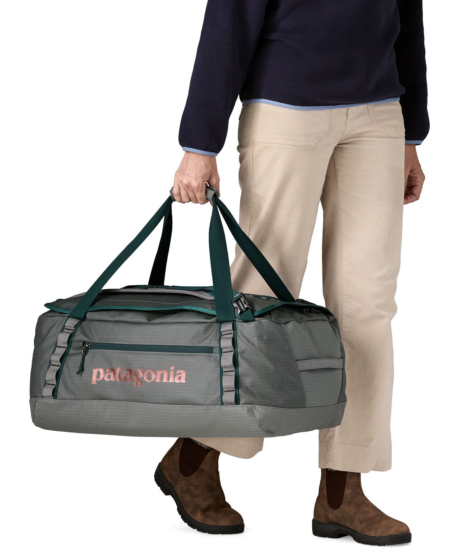 A woman carrying the Patagonia black hole 55L duffel bag in noble grey available at Babipur. 