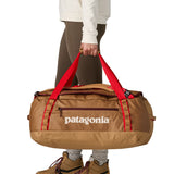 A woman carrying the Patagonia black hole 55L duffel bag in talon gold available at Babipur. 
