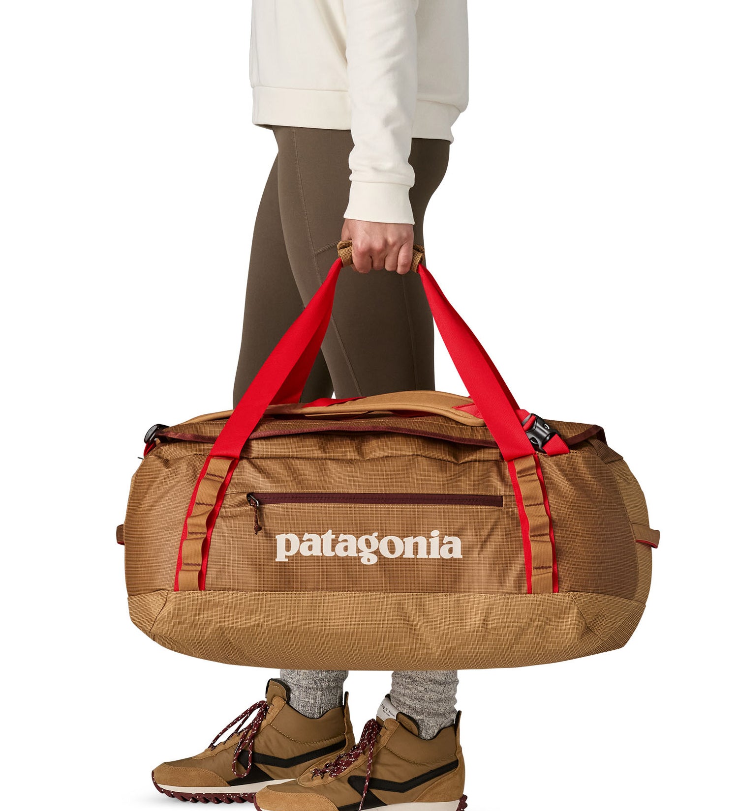 A woman carrying the Patagonia black hole 55L duffel bag in talon gold available at Babipur. 