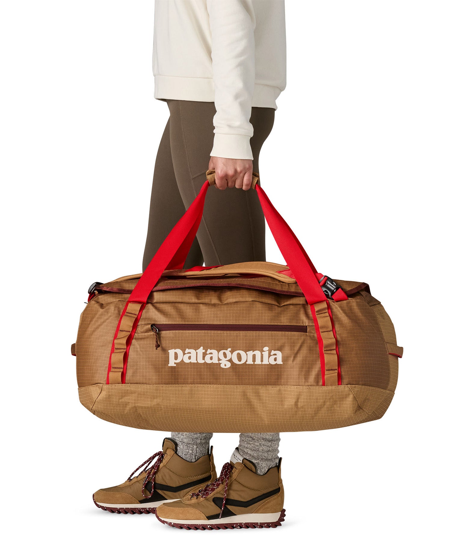 A woman carrying the Patagonia black hole 55L duffel bag in talon gold available at Babipur. 