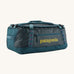 Patagonia black hole 55L duffel bag in tidal teal / luminous pink available at Babipur. A dark teal colour bag with pink trim and a mustard colour branding  on the side. Features shoulders straps and a handle on the top for easy carrying.