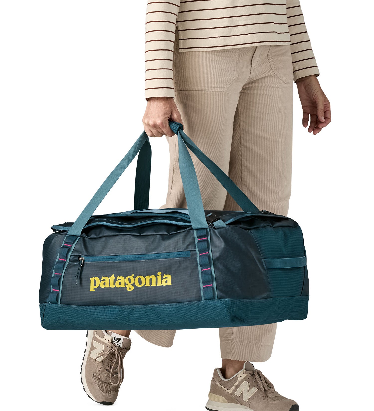 A woman carrying the Patagonia black hole 55L duffel bag in tidal teal / luminous pink available at Babipur. 