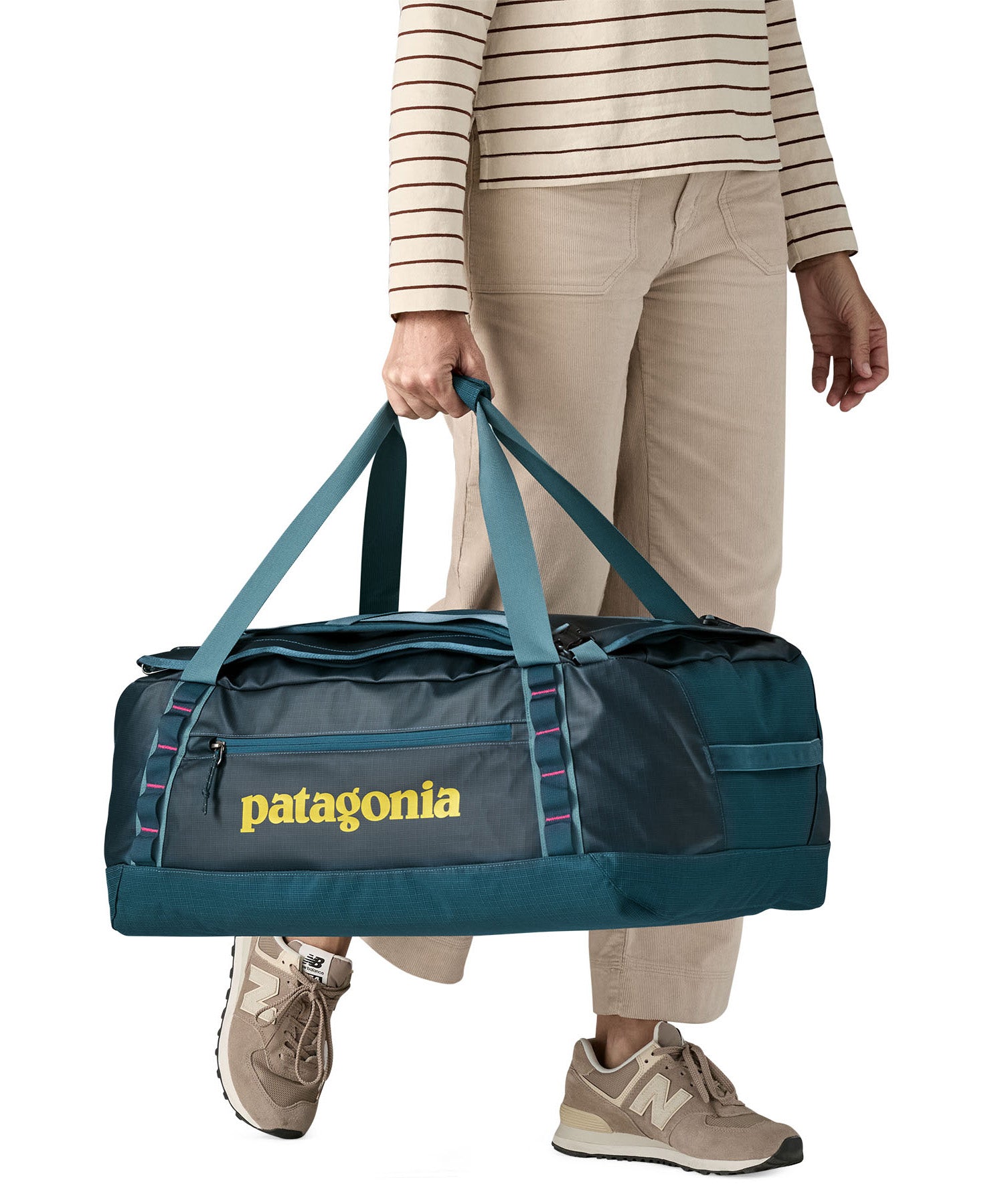 A woman carrying the Patagonia black hole 55L duffel bag in tidal teal / luminous pink available at Babipur. 