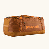 Patagonia black hole 70L duffel bag in Cinnamon Brown. A Rusty brown/orange body with matching trim and Patagonia branding on the side. Features shoulder straps and a handle on the top for easy carrying.
