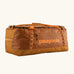 Patagonia black hole 70L duffel bag in Cinnamon Brown. A Rusty brown/orange body with matching trim and Patagonia branding on the side. Features shoulder straps and a handle on the top for easy carrying.