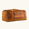 Patagonia black hole 70L duffel bag in Cinnamon Brown. A Rusty brown/orange body with matching trim and Patagonia branding on the side. Features shoulder straps and a handle on the top for easy carrying.