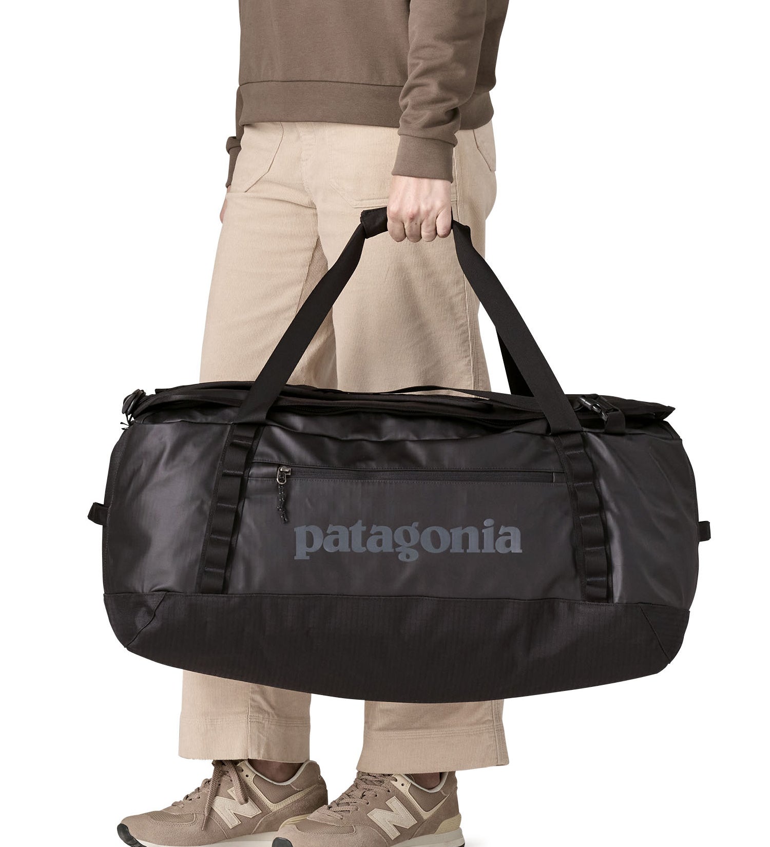 A woman carrying the Patagonia black hole 70L duffel bag in black on black available at Babipur. 