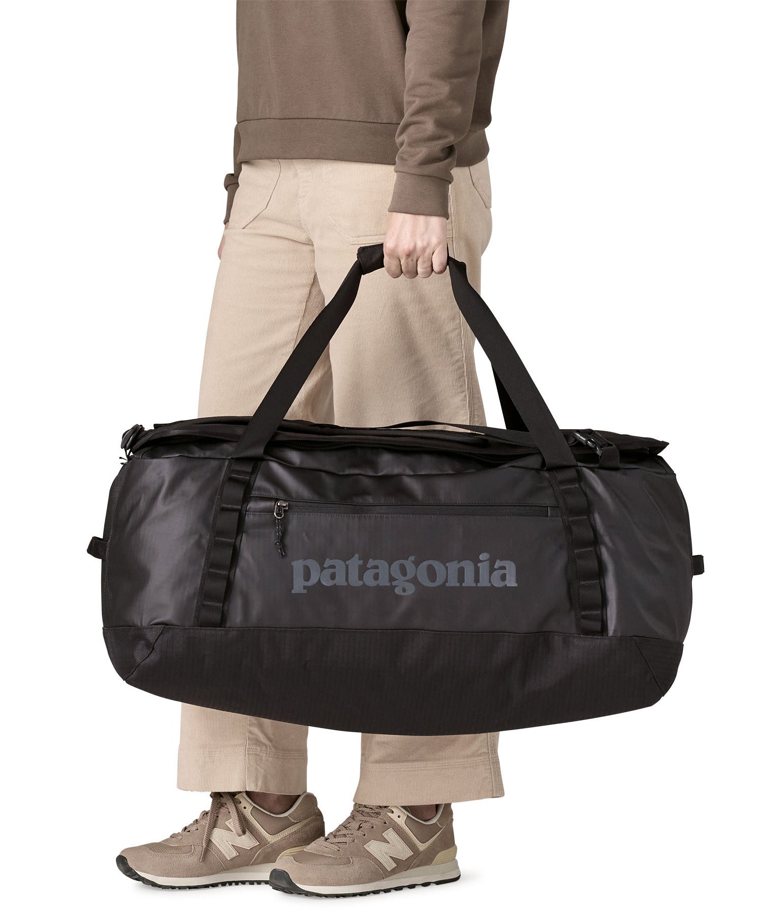 A woman carrying the Patagonia black hole 70L duffel bag in black on black available at Babipur. 