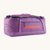 Patagonia black hole 70L duffel bag in brisk purple available at Babipur. A bright purple bag with orange branding on the side. Features shoulders straps and a handle on the top for easy carrying.