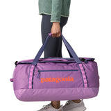 A woman carrying the Patagonia black hole 70L duffel bag in brisk purple available at Babipur. 