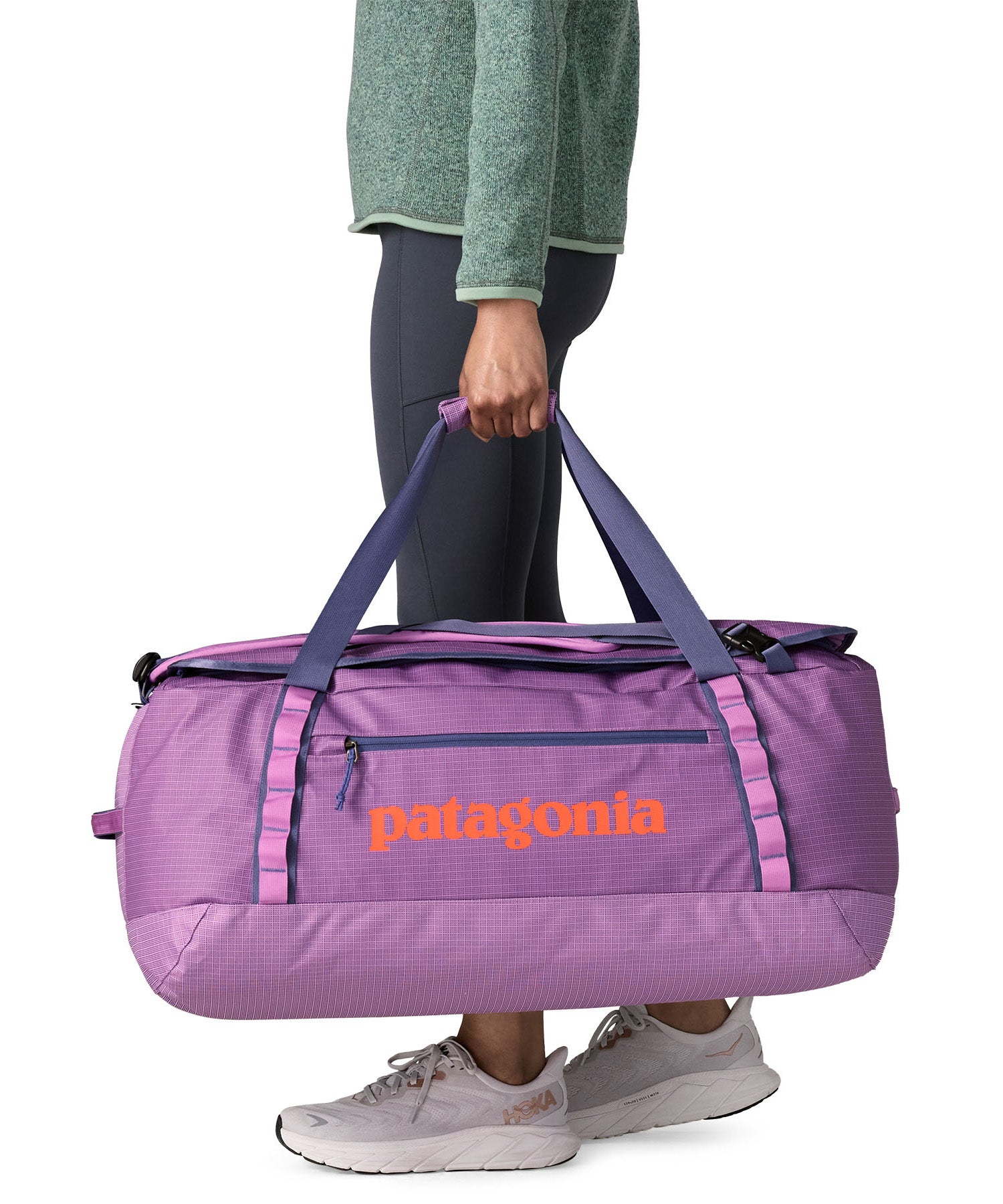 A woman carrying the Patagonia black hole 70L duffel bag in brisk purple available at Babipur. 