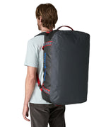 A man carrying the Patagonia black hole 70L duffel bag in smolder blue / amanita red on his back by the shoulder straps. Backpack available at Babipur. 