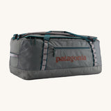 Patagonia black hole 70L duffel bag in noble grey available at Babipur. A dark grey bag with green trim and brown branding on the side. Features shoulders straps and a handle on the top for easy carrying.