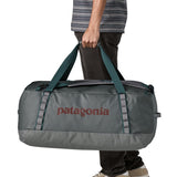 A man carrying the Patagonia black hole 70L duffel bag in noble grey available at Babipur. 
