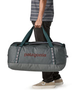 A man carrying the Patagonia black hole 70L duffel bag in noble grey available at Babipur. 