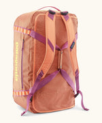 Patagonia black hole 70l duffel bag in bright orange with matching shoulder straps and extra purple carry handles