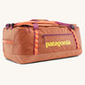 Patagonia black hole 70l duffel bag in bright orange with purple zip details, straps and yellow printed logo on front panel 