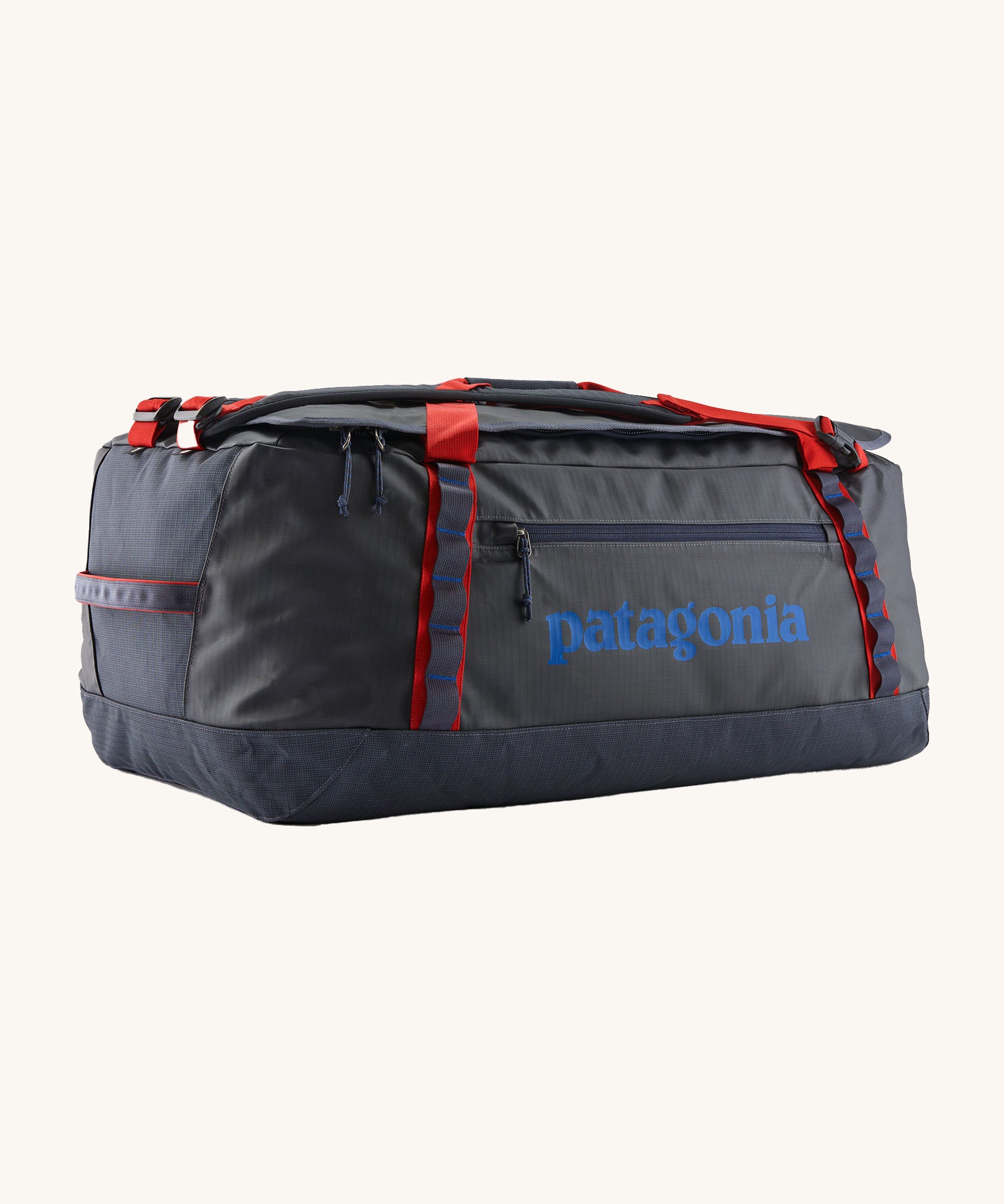 Patagonia black hole 70L duffel bag in smolder blue / amanita red available at Babipur. A dark blue bag with red trim and blue branding on the side. Features shoulders straps and a handle on the top for easy carrying.