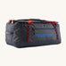 Patagonia black hole 70L duffel bag in smolder blue / amanita red available at Babipur. A dark blue bag with red trim and blue branding on the side. Features shoulders straps and a handle on the top for easy carrying.