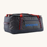 Patagonia black hole 70L duffel bag in smolder blue / amanita red available at Babipur. A dark blue bag with red trim and blue branding on the side. Features shoulders straps and a handle on the top for easy carrying.