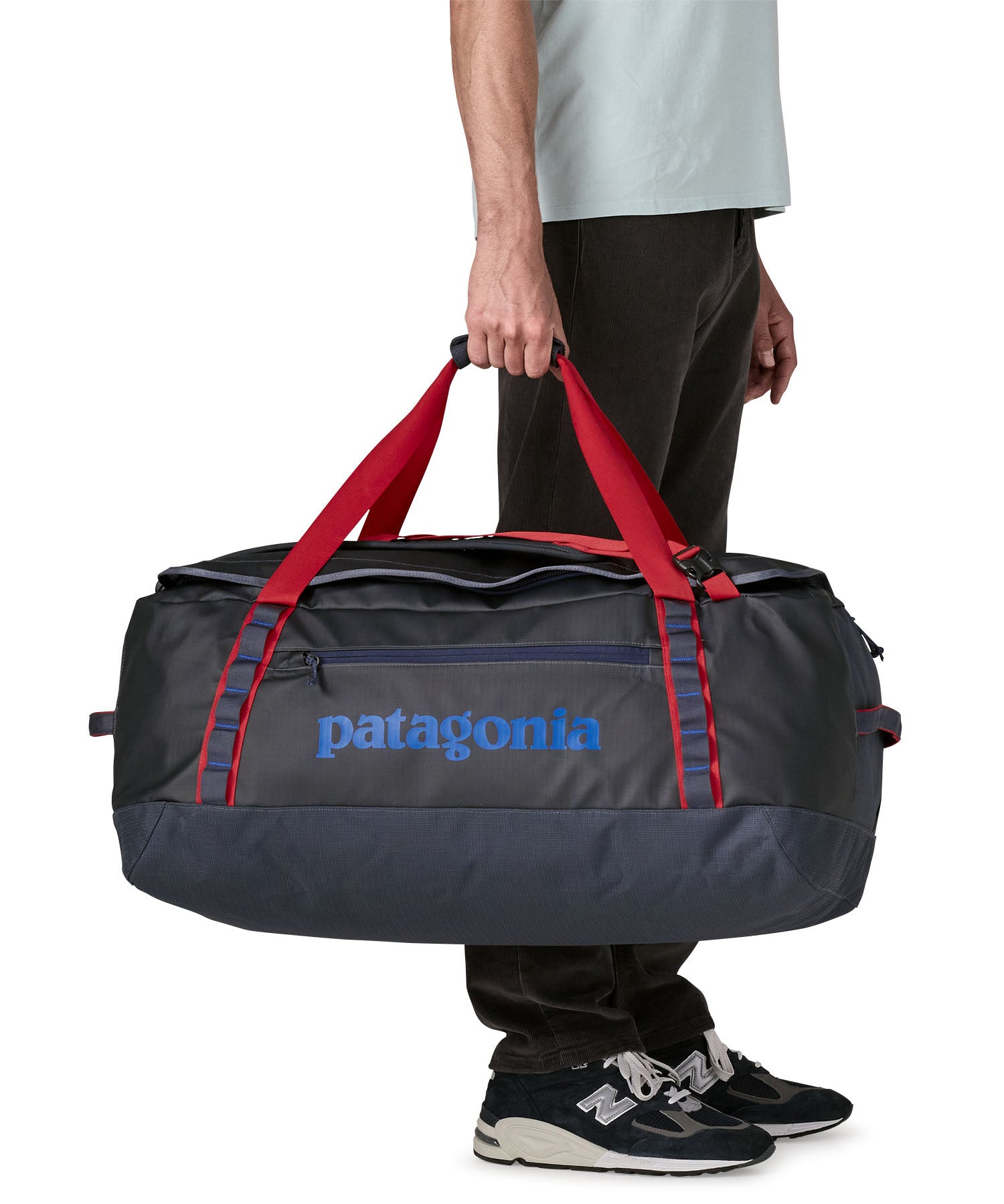 A man carrying the Patagonia black hole 70L duffel bag in smolder blue / amanita red available at Babipur. 