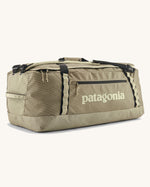 Patagonia black hole 70l duffel bag in pale green with black zip details, straps and cream printed logo on front panel 