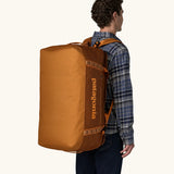 Man carrying Patagonia Black Hole Duffel 70L in Cinnamon Brown on his back with shoulder straps.