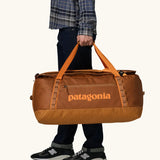 Patagonia Black Hole Duffel 70L in Cinnamon Brown. Bag being held by handle straps. 