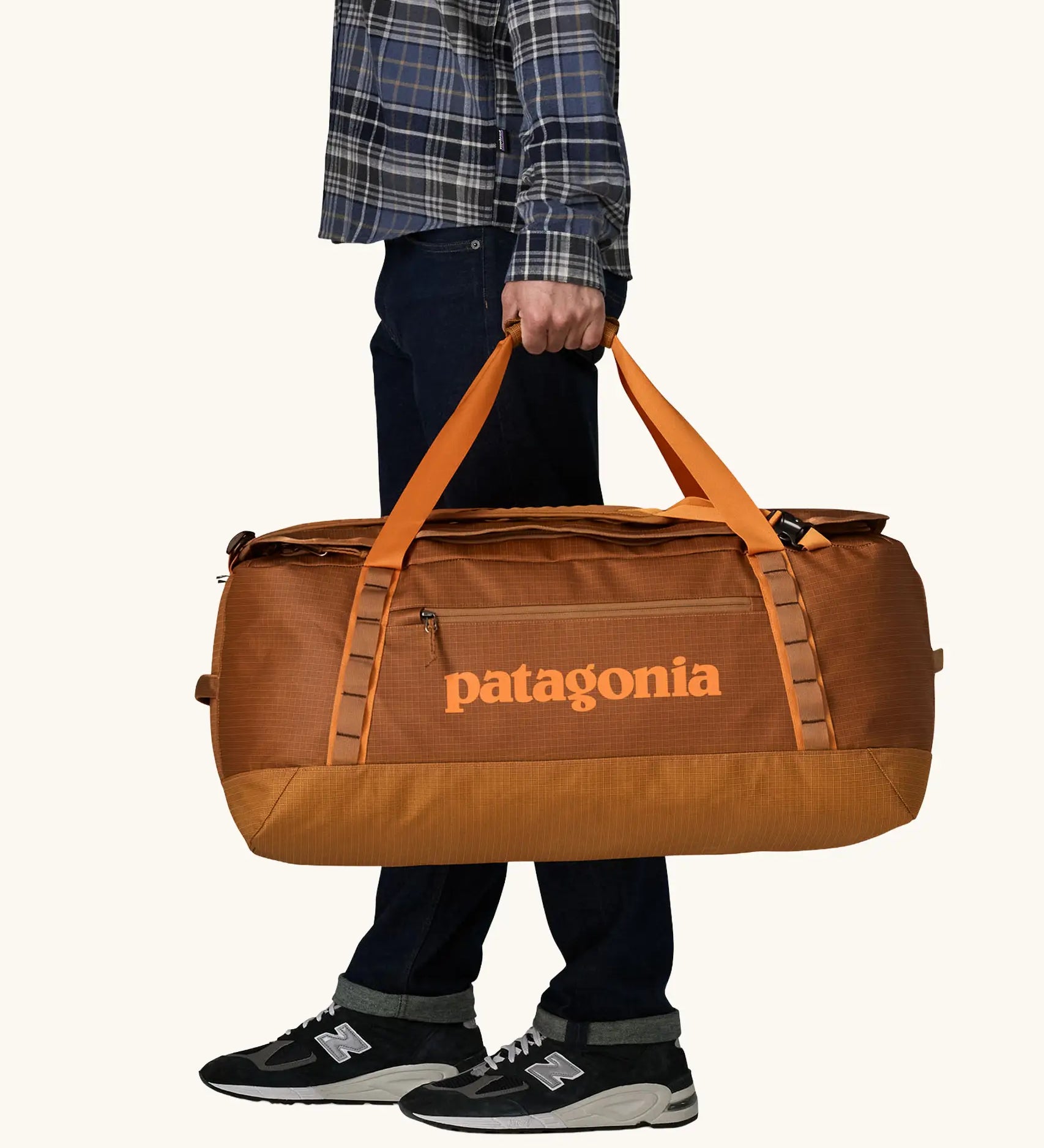 Patagonia Black Hole Duffel 70L in Cinnamon Brown. Bag being held by handle straps. 
