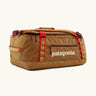 Patagonia black hole 40l duffel bag in talon gold with brown zip details and cream printed logo.