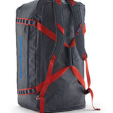 A close up of the Patagonia black hole 100L duffel bag in smolder blue / amanita red available at Babipur showing the shoulder straps and carry straps with red trim detail