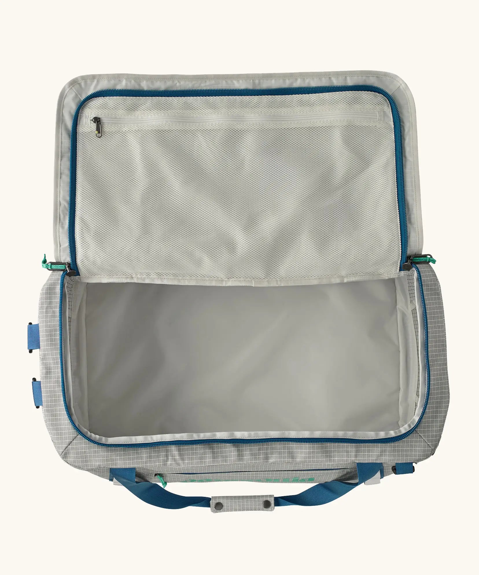 An open Patagonia black hole 55l duffel bag in birch white showing zipped compartment on the inside of the lid