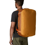 Back of man carrying the Patagonia black hole 55L duffel bag in Cinnamon brown showing the protective panel on the underside of the bag